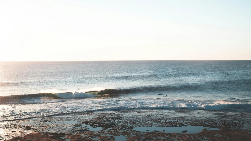 a man riding a wave on top of a surfboard, unsplash contest winner, minimalism, australian beach, early evening, panoramic shot, beach on the outer rim