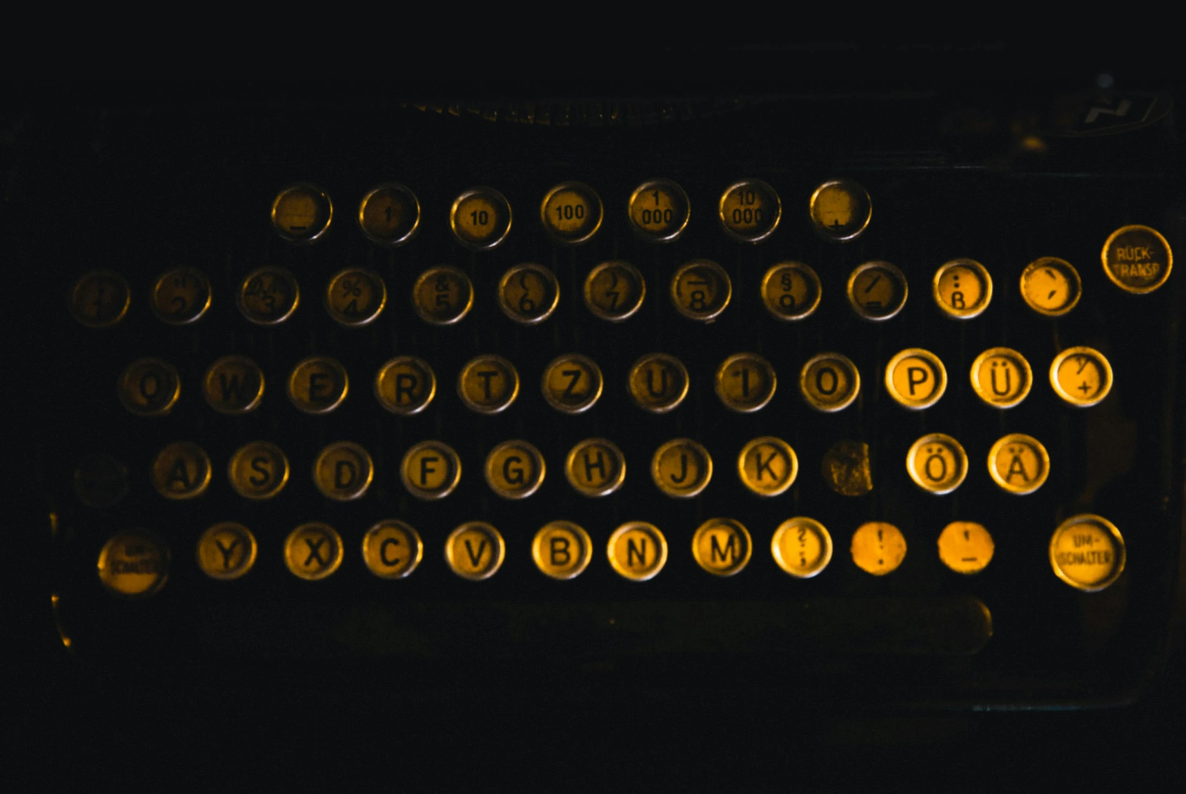 a close up of a typewriter in the dark, by Emma Andijewska, unsplash, synthetism, gold and black color scheme, brown, snapchat photo, multiple stories