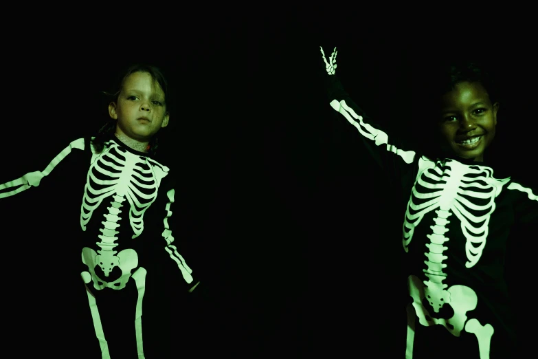 a couple of young children standing next to each other, by Stephen Bone, interactive art, glowing bones, halloween film, studio bones, 2 0 1 0 s
