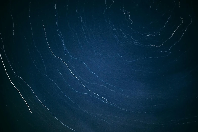 a man riding a snowboard on top of a snow covered slope, an album cover, pexels, space art, glowing tiny blue lines, midnight-blue, close-up print of fractured, spiral lines