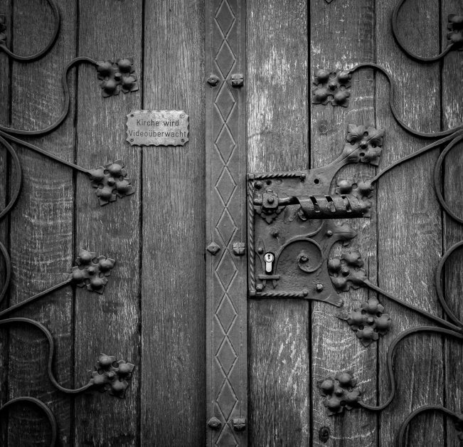 a black and white photo of a wooden door, by Andries Stock, pexels, gothic art, made of intricate metal and wood, lock, medieval photograph, stealthy