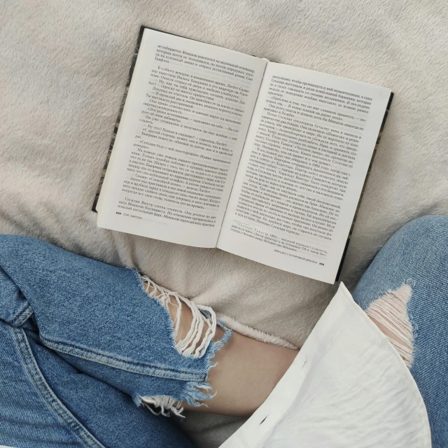 a person laying on a bed reading a book, by Matija Jama, pexels contest winner, ripped jeans, soft outline, dressed casually, ripped fabric