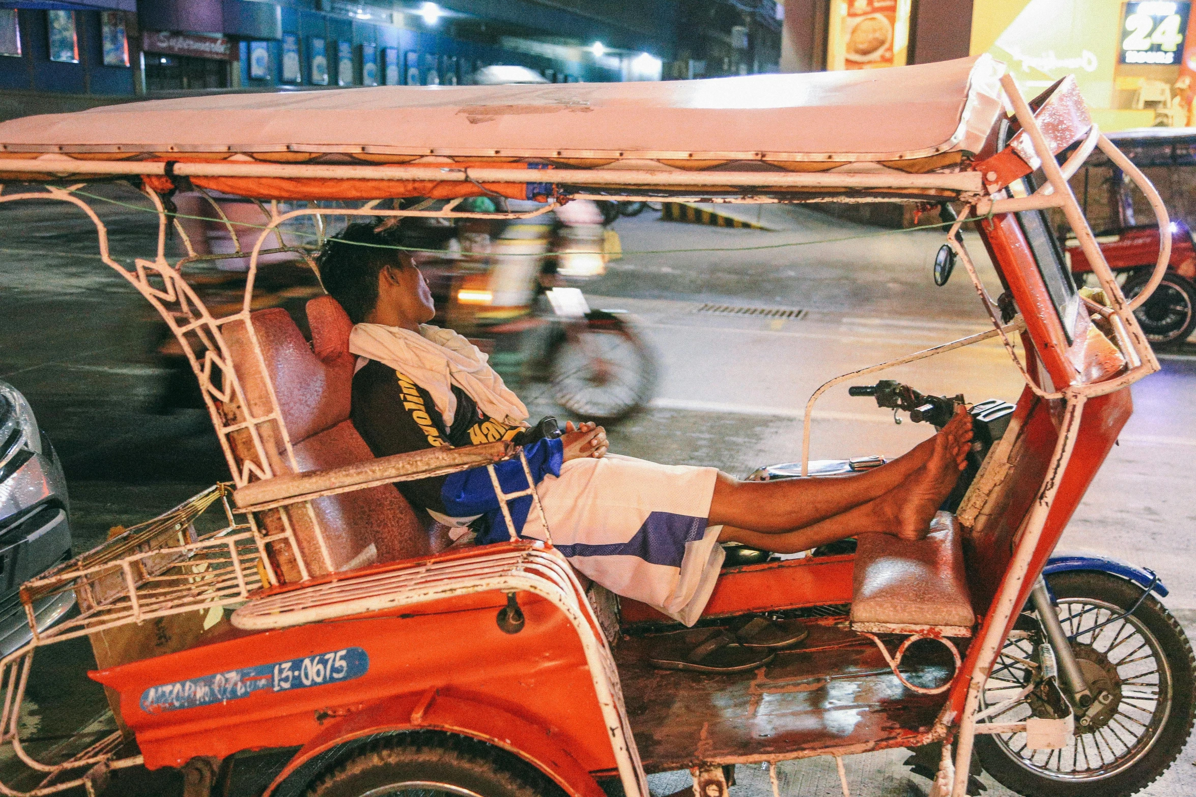 a man sitting in a tuk - tuk on a city street, pexels contest winner, philippines, thumbnail, sprawled out, warm glow