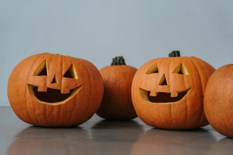 a group of carved pumpkins sitting on top of a table, pexels, avatar image, on a gray background, rule of three, background image