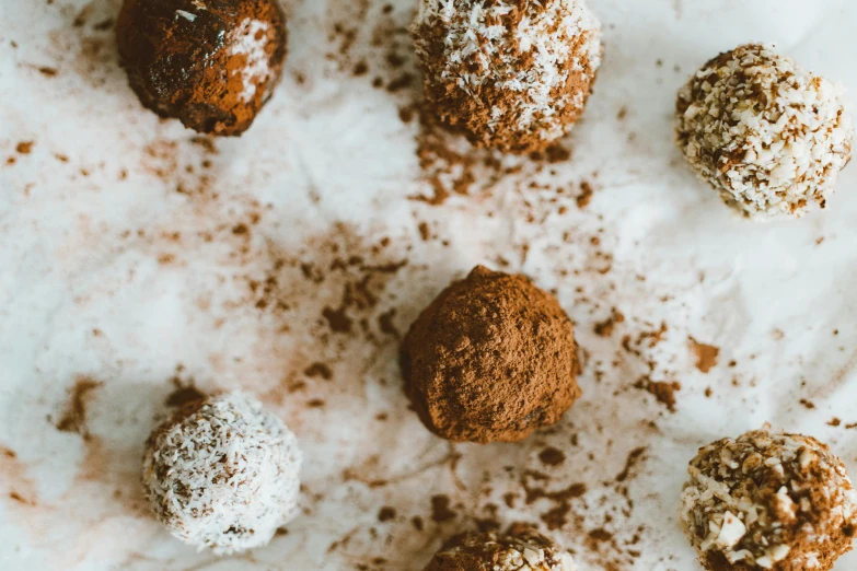 a table topped with chocolate balls covered in powdered sugar, by Emma Andijewska, trending on pexels, 🦩🪐🐞👩🏻🦳, brown haired, sustainable materials, background image