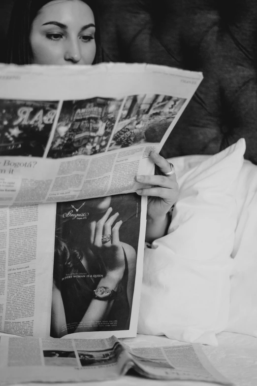 a black and white photo of a woman reading a newspaper, by Adam Marczyński, pexels contest winner, laying on her back, gif, romance, magazines