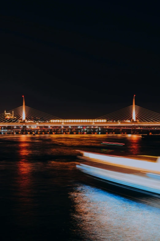 a boat in the water with a bridge in the background, at night time, bangkok, zoomed in shots, lasers