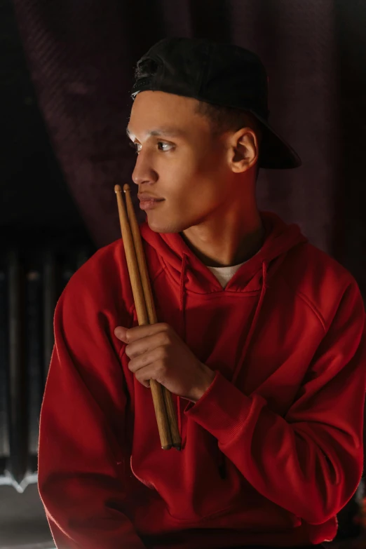 a man in a red hoodie holding a pair of drums, pexels contest winner, realism, headshot profile picture, ashteroth, ( low key light ), male teenager