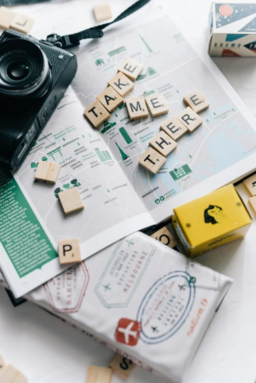 a camera sitting on top of a table next to a book, building blocks, tourist map, green letters, flatlay