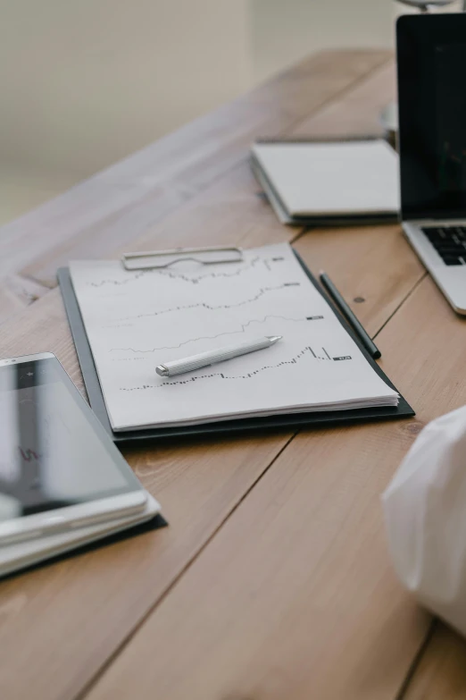 a laptop computer sitting on top of a wooden table, analytical art, writing on a clipboard, on a white table, uploaded, multiple stories