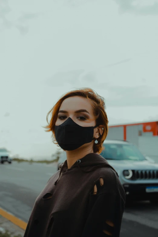 a woman standing on the side of the road wearing a face mask, by Adam Marczyński, pexels contest winner, photograph of a techwear woman, outside in parking lot, portrait of apex legends, low quality video