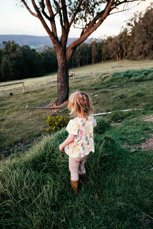 a little girl that is standing in the grass, by Jessie Algie, pexels contest winner, in australia, be running up that hill, printed on a cream linen t-shirt, back view also