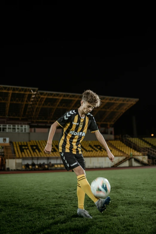 a man kicking a soccer ball on a field, inspired by Jan Verkolje, pexels contest winner, happening, blonde boy with yellow eyes, during the night, 8k octan advertising photo, square