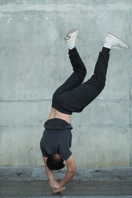 a man doing a handstand in front of a concrete wall, heavily upvoted, sports clothing, scientific photo, grey