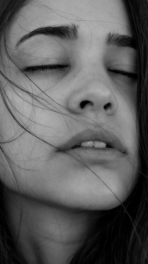 a black and white photo of a woman with her eyes closed, inspired by irakli nadar, unsplash, conceptual art, natural lips, exhausted face close up, young girl, 🤤 girl portrait