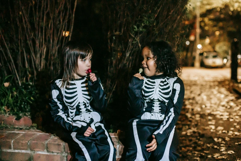 two little girls dressed up in skeleton costumes, a cartoon, by Helen Stevenson, pexels contest winner, night outside, wearing a tracksuit, fujifilm”, 💋 💄 👠 👗