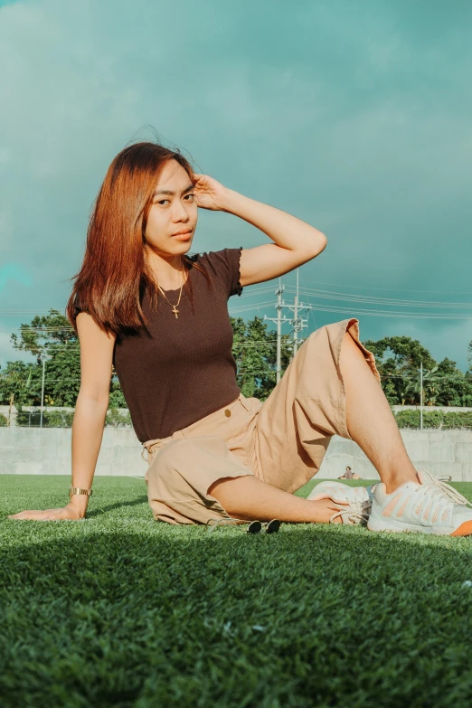 a woman sitting on top of a lush green field, by Robbie Trevino, trending on pexels, realism, brown shirt, casual streetwear, portrait of modern darna, khakis