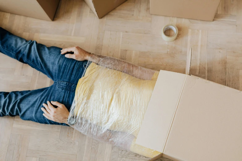 a man laying on the floor next to a cardboard box, inspired by Sarah Lucas, pexels contest winner, renaissance, cracked plastic wrap, headless, gif, fully functional