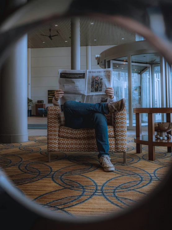 a person sitting in a chair reading a newspaper, a picture, by Sebastian Spreng, pexels contest winner, in a hotel hallway, sitting on the couch, cool marketing photo, spying