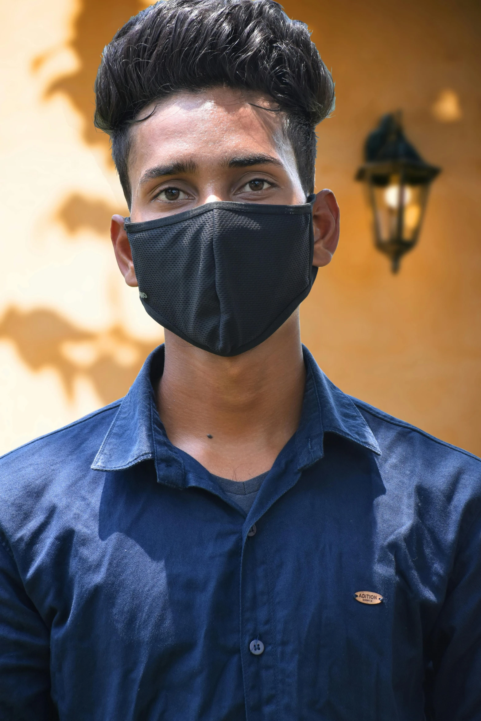 a man in a blue shirt wearing a black face mask, bangladesh, 1 6 years old, featured face details, wearing a black tshirt