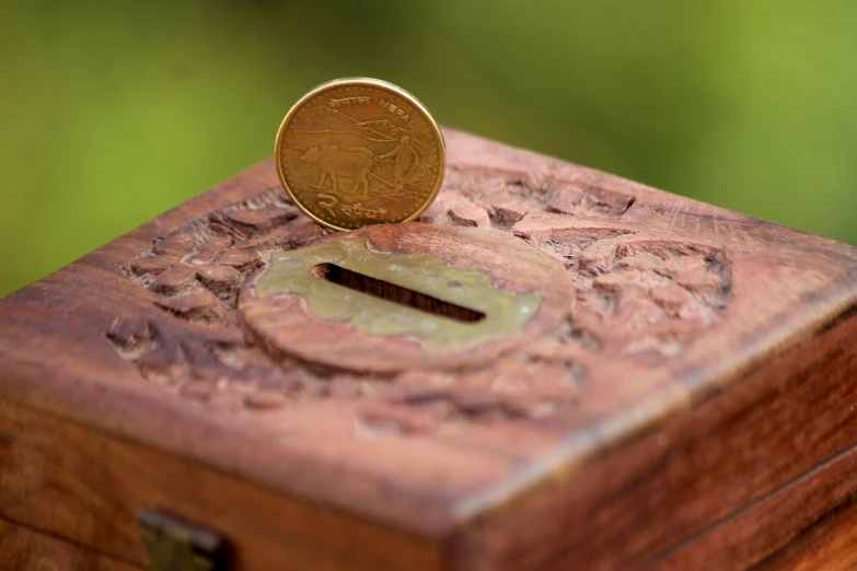 a coin sitting on top of a wooden box, inspired by Eden Box, pexels contest winner, letterbox, india, banknote, al fresco