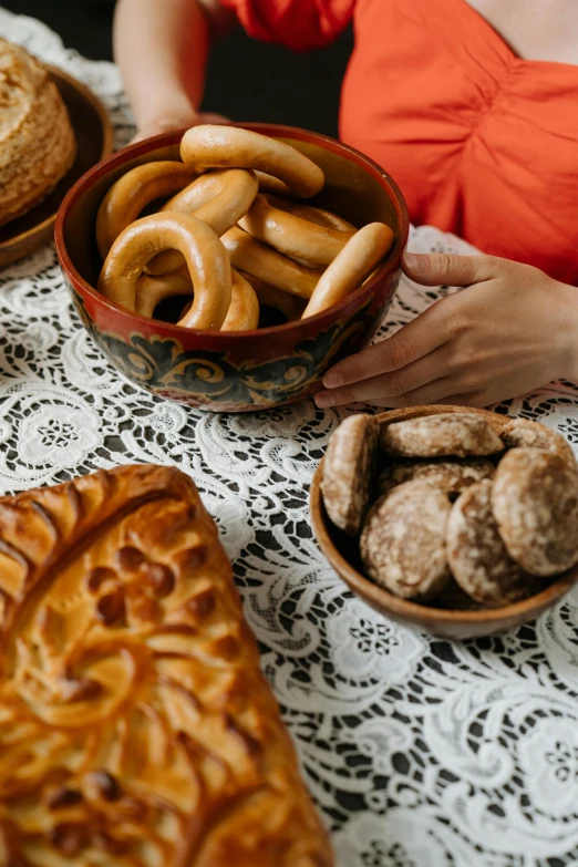 a woman sitting at a table with a variety of pastries, pexels contest winner, baroque, bowl filled with food, samarkand, bagels, breakfast at las pozas
