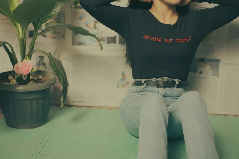 a woman sitting on the floor with her hands behind her head, an album cover, inspired by Elsa Bleda, trending on pexels, kawaii shirt and jeans, long sleeve, green and red tones, black bodysuit