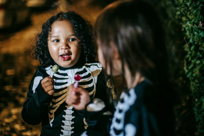 a little girl dressed up in a skeleton costume, by Lee Loughridge, pexels contest winner, an ewok eating a lollipop, ska skeleton and girlfriend, (night), medium close up