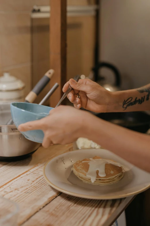 a person preparing food on a wooden table, by Jessie Algie, trending on pexels, pancake flat head, bowl, blue, melbourne