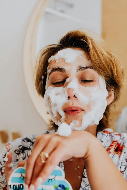 a woman is shaving her face in front of a mirror, by Julia Pishtar, trending on pexels, covered in white flour, bubble bath, polka dot, a person with a raccoon head