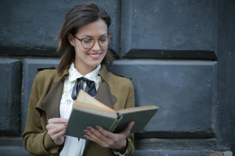 a woman in glasses is reading a book, a portrait, pexels contest winner, wearing a trenchcoat, school curriculum expert, handsome girl, wearing jacket and skirt