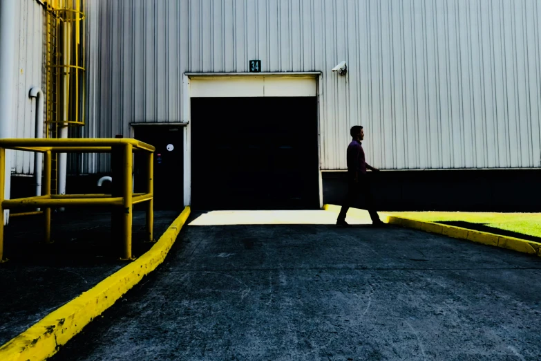 a man that is standing in front of a building, by Andrew Domachowski, unsplash, postminimalism, warehouses, walking down, ignant, high resolution print :1 cmyk :1