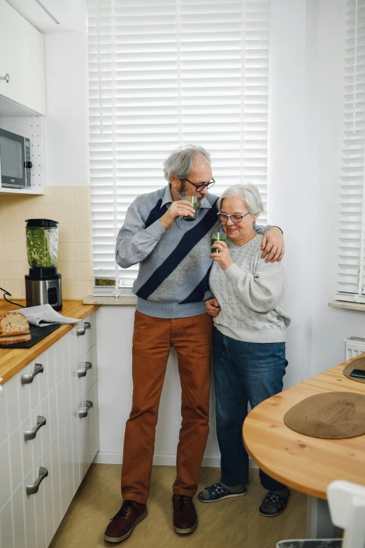 a man standing next to a woman in a kitchen, by Adam Marczyński, pexels contest winner, two old people, 2 5 6 x 2 5 6 pixels, drinking a cup of coffee, hugging