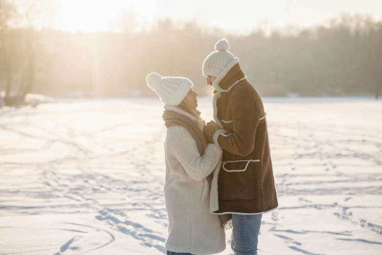 a man and a woman standing in the snow, pexels contest winner, symbolism, afternoon sunshine, winter lake setting, white, tan