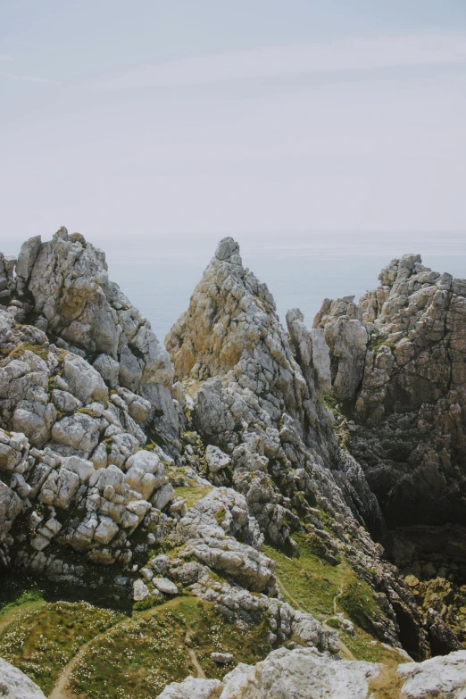 a herd of sheep standing on top of a lush green hillside, by Juan Giménez, les nabis, rocky coast, asymmetrical spires, crisp lines, layers of strata