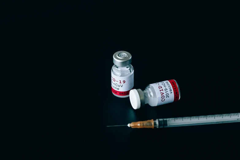a syll sitting on top of a table next to a bottle of medicine, a picture, pexels, hyperrealism, syringe, with a black background, background image, virus