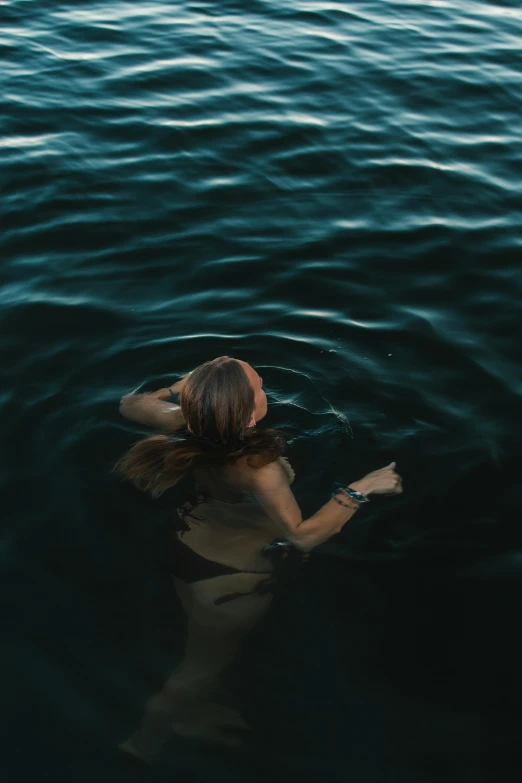 a woman swimming in a body of water, inspired by Elsa Bleda, pexels contest winner, renaissance, dark ocean, summer evening, down there, slightly tanned