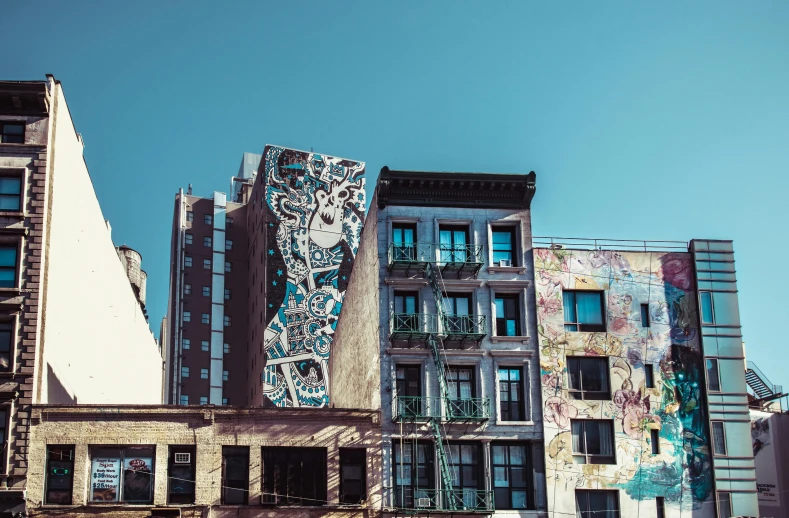 a building with a mural on the side of it, inspired by Elsa Bleda, pexels contest winner, new york buildings, james jean ”, blue sky, slide show