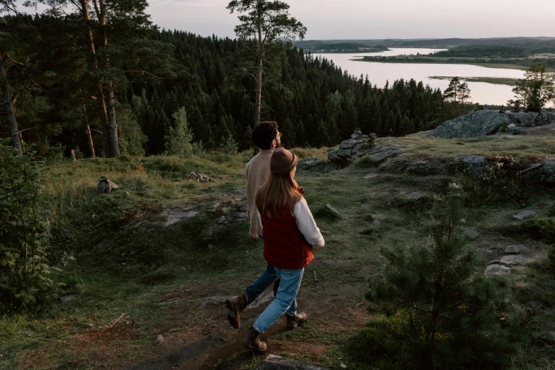 a man and a woman walking up a hill, by Jesper Knudsen, pexels contest winner, forest with lake, late summer evening, view from back, view(full body + zoomed out)