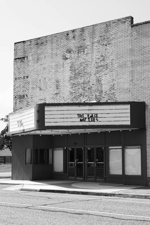 a black and white photo of a movie theater, tally hall, front view, tear, past