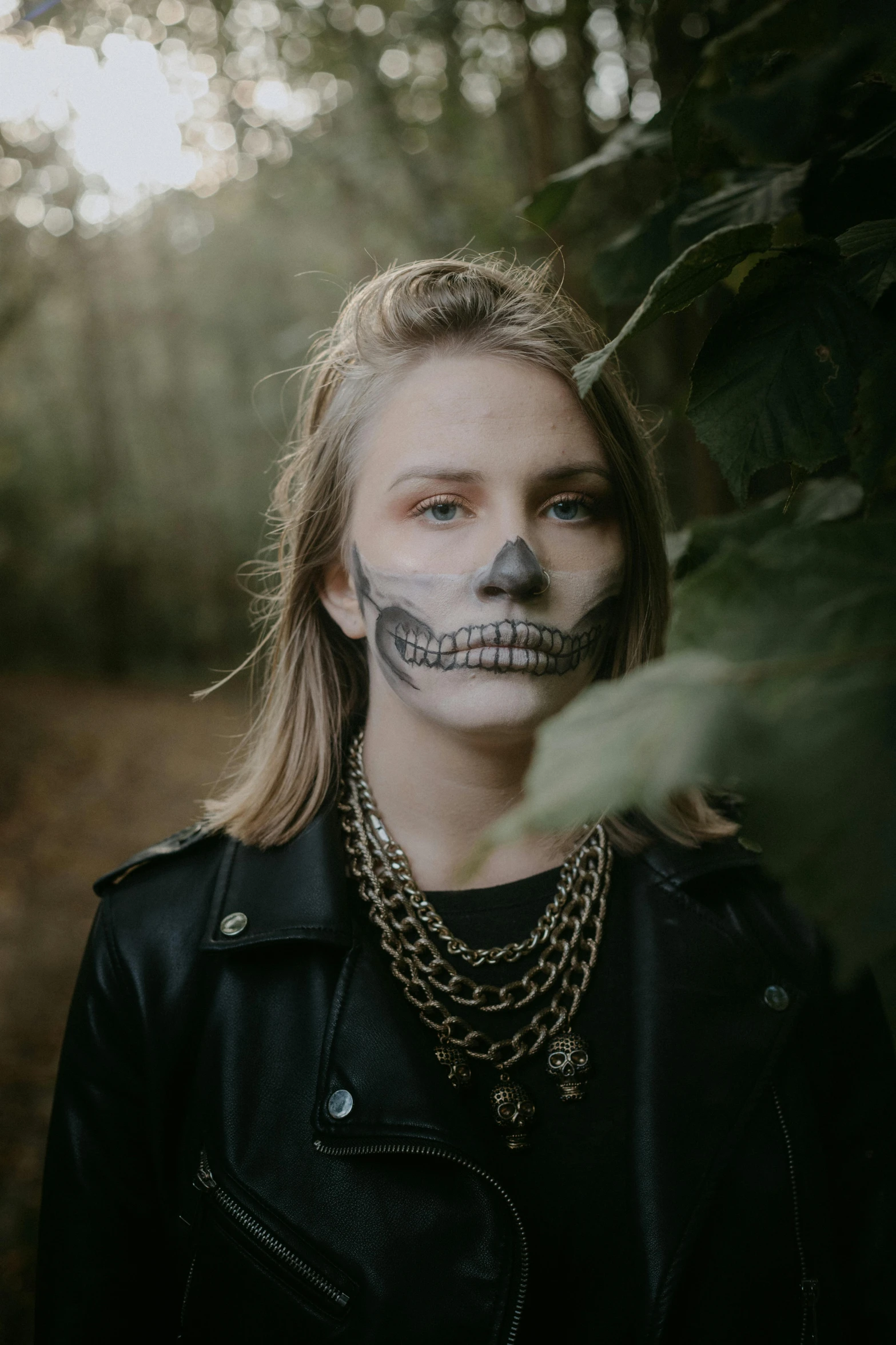 a woman with a skeleton face painted on her face, inspired by Elsa Bleda, trending on pexels, a man wearing a black jacket, bone jewellery, headshot profile picture, autumn season