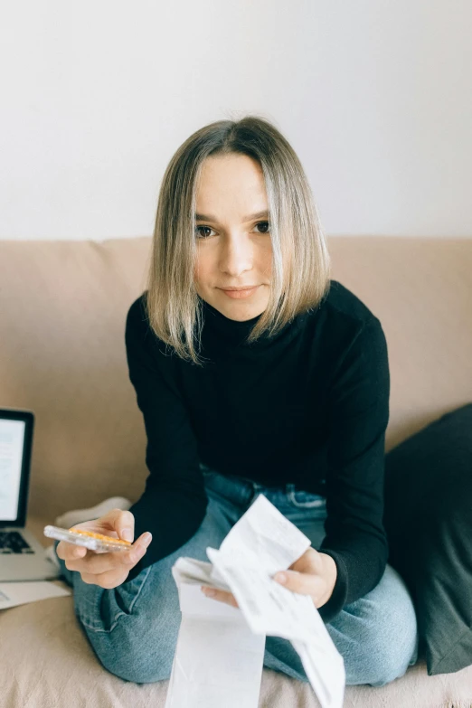 a woman sitting on a couch in front of a laptop, a portrait, inspired by Louisa Matthíasdóttir, pexels contest winner, wearing turtleneck, pen and paper, russian girlfriend, she is holding a smartphone