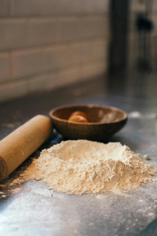 a rolling pin sitting on top of a counter next to a pile of flour, a still life, unsplash, made of glazed, hot food, wide, powder