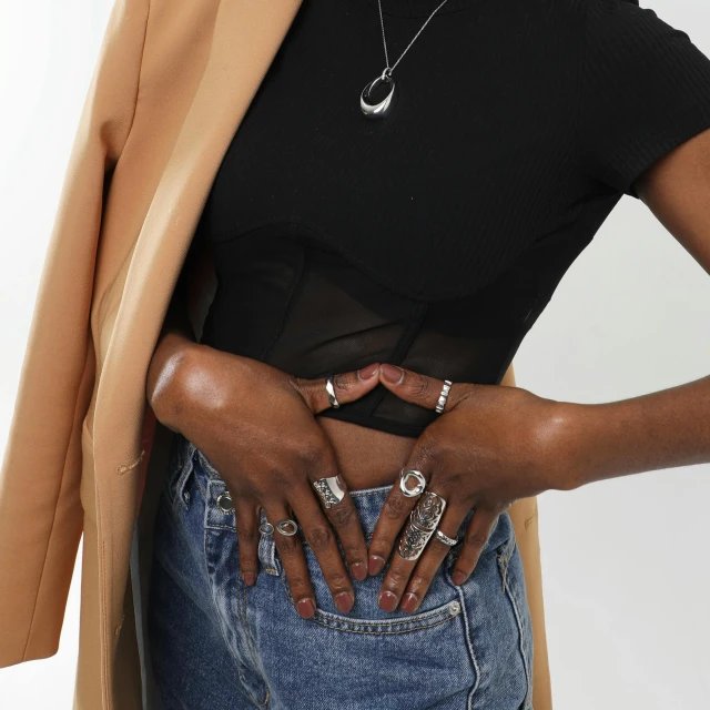 a woman standing with her hands on her hips, inspired by L. A. Ring, happening, silver accessories, zoomed out shot, hands straight down, dark skinned