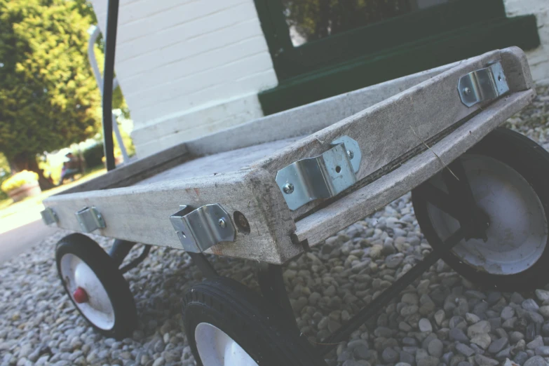 a wooden cart sitting on top of a gravel road, on a wooden tray, grey, hardware, colour corrected