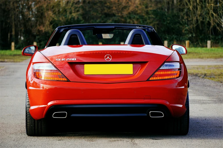 a red sports car parked on the side of the road, by Tom Bonson, shutterstock, mercedes, back of head, open top, full colour