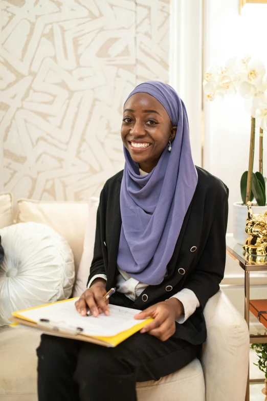 a woman sitting on a couch in a living room, by Arabella Rankin, hurufiyya, white hijab, vp of marketing, student, riyahd cassiem