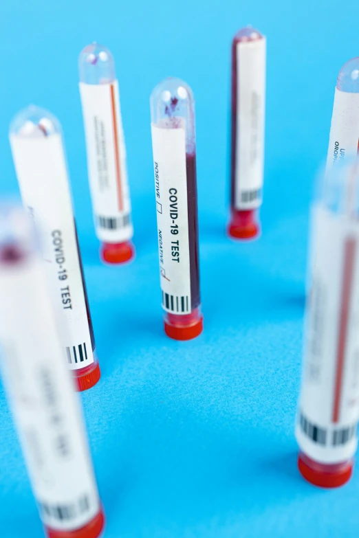 a group of blood tubes sitting on top of a blue surface, labels, diagnostics, thumbnail, vibrant colour