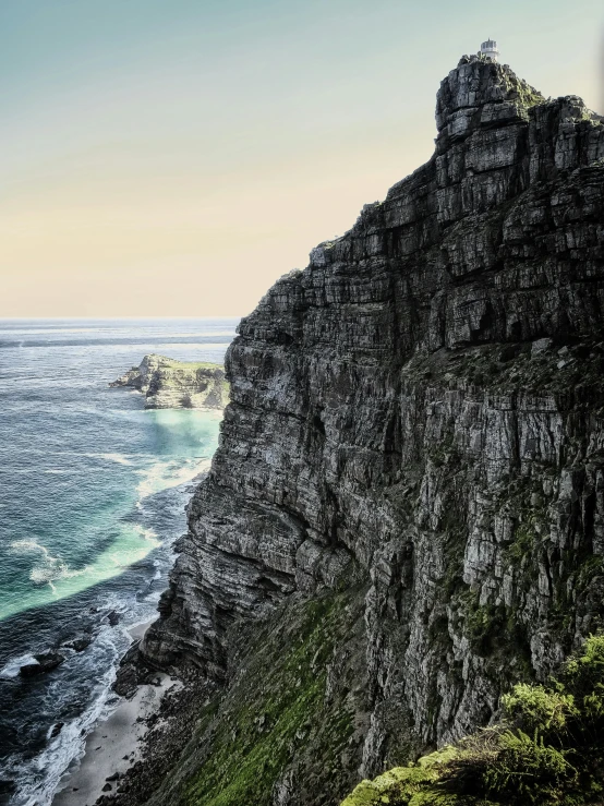 a man standing on top of a cliff next to the ocean, south african coast, hyper - detailed color photo, today\'s featured photograph 4k, multiple stories