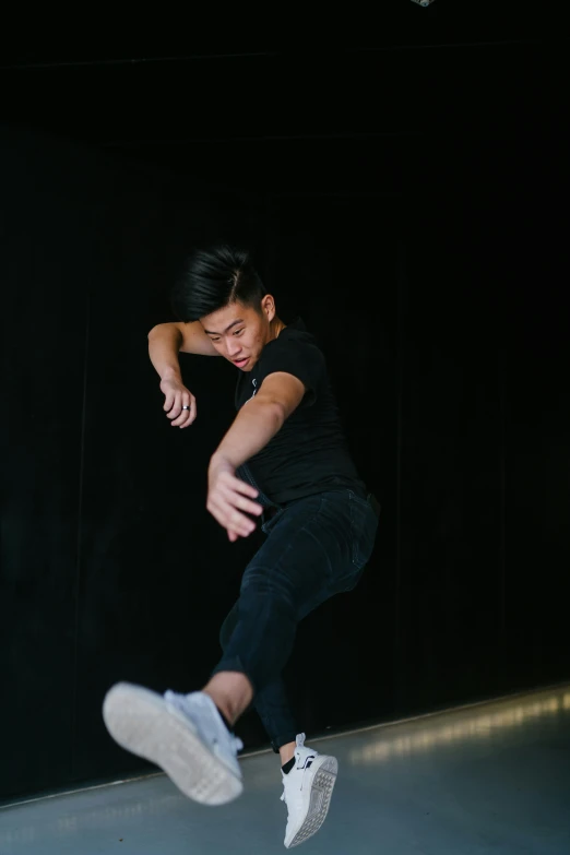 a man flying through the air while riding a skateboard, trending on unsplash, happening, asian human, standing with a black background, low quality photo, teenage boy